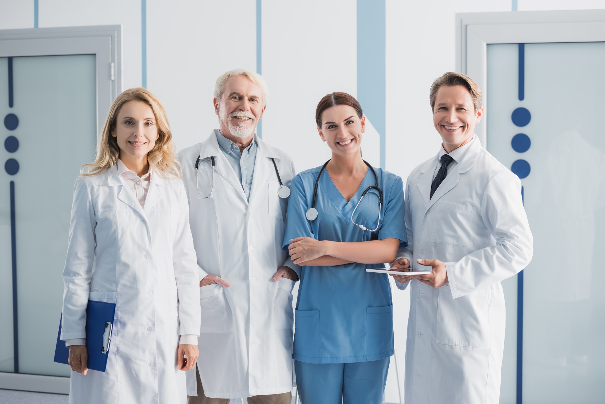 Hospital staff with digital tablet and clipboard looking at camera